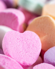 Pink Conversation Heart up close with other hearts around.  Pastel colors.