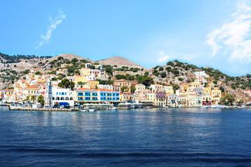 Fototapeta na wymiar Bell-tower and colorful neoclassical houses in harbor town of Symi (Symi Island, Greece)