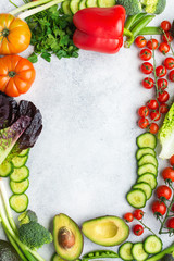 Fresh raw ingredients tomatoes cucumbers lettuce pepper avocado parsley spring onion broccoli peas on the white table, top view, copy space, selective focus