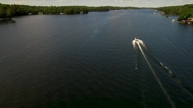 A white motor boat travels across a calm lake.