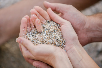 couple in love, male and female Hands holding a sand shell in form of the heart 