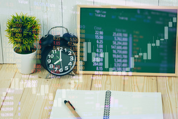 Double exposure of alarm clock with green chalkboard, notebook and financial graph, with candle stick and stock market screen, business planning vision and finance analysis.