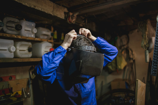 Portrait of a young man wearing welding mask in his workshop.