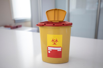 Yellow biohazard medical contaminated sharps clinical waste container isolated on white background.