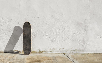 Skateboard on deteriorated white wall during a sunny afternoon with big copy space. Skateboarding...