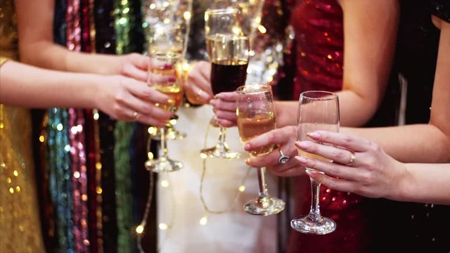 Slow motion of glasses with champagne and red wine. Unidentified women in cocktail dresses are celebrating with champagne. Office party