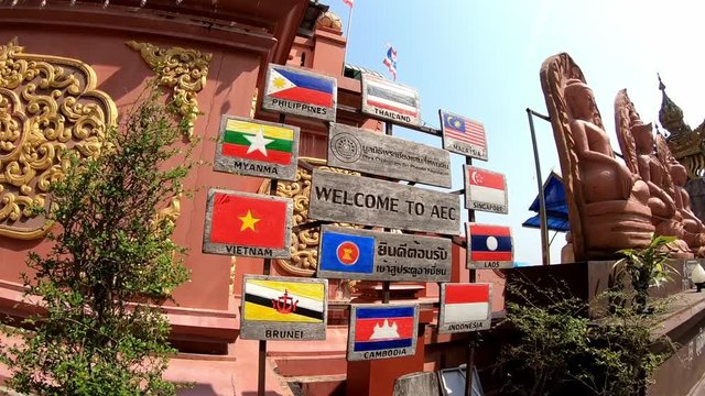 Golden triangle in Thailand: the sign "Welcome to AEC" and sitting Buddha statues. Viedeo is moving to the left.