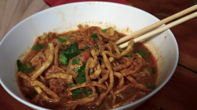 Fingers grabbing food beautiful bowl of Spicy Curry Noodle soup. Khao Sawy.