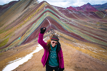 Junge Frau feiert mit erhobener Faust nach einem langen Trekking durch Vinicunca (Regenbogenberg) Peru.