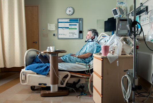 Side View Of Man Sitting On Bed In Hospital