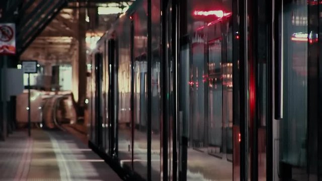 Automatic doors close at the departing high-speed train at Moscow Central Ring (MCC) station of the Moscow Central Ring (MCC) railroad. Telephoto shot. Unrecognizable people silhouettes
