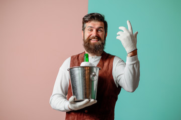 Waiter holds wine cooler with bottle of champagne. Waiter in high class restaurant serving wine or...