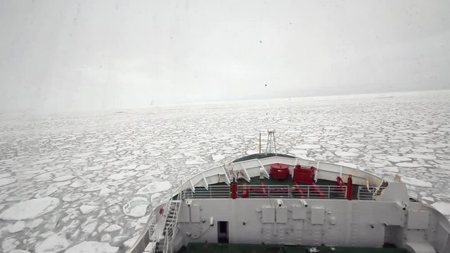 Research icebreaker cruising at the pancake ice formations of the marginal ice zone of Antarctica during winter