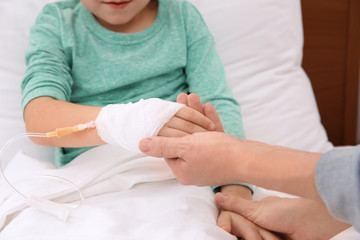 Woman visiting her little child with intravenous drip in hospital, closeup