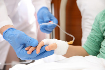 Obraz premium Doctor adjusting intravenous drip for little child in hospital, closeup