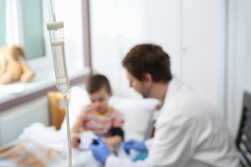 Obraz premium Doctor examining little child in hospital, focus drip chamber