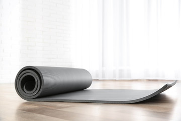 Rolled grey yoga mat on floor indoors
