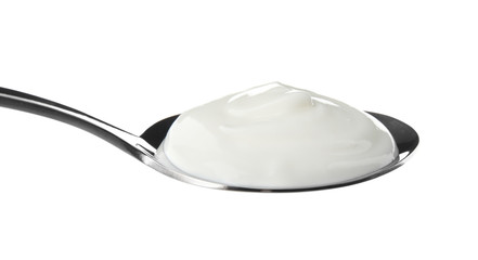 Spoon with creamy yogurt on white background, closeup