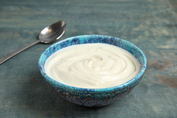 Bowl with creamy yogurt on blue wooden background