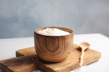 Wooden bowl with creamy yogurt served on table