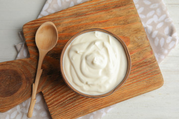 Wooden bowl with creamy yogurt served on table, top view