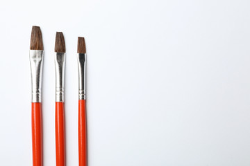 Fototapeta premium Different paint brushes on white background, top view. Space for text