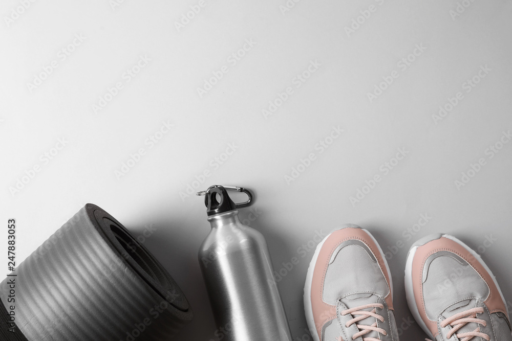 Poster Yoga mat, sneakers and bottle of water on light background, top view with space for text. Fitness gym equipment