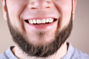 Young man with healthy teeth smiling on color background, closeup