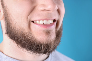 Obraz premium Young man with healthy teeth and beautiful smile on color background, closeup