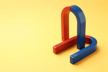 Red and blue horseshoe magnets on color background. Space for text