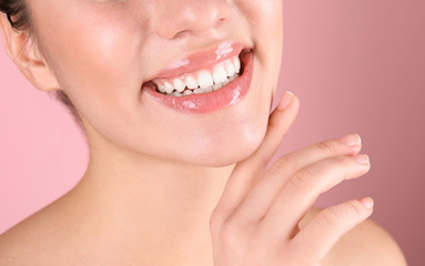 Beautiful young woman with healthy teeth on color background, closeup