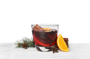 Glass of mulled wine with fir branch, cinnamon and orange on table against white background