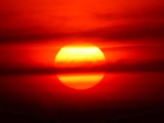 Beautiful big sunset over sea. Tranquil scene of Closeup red sun and red sky sunset over the ocean