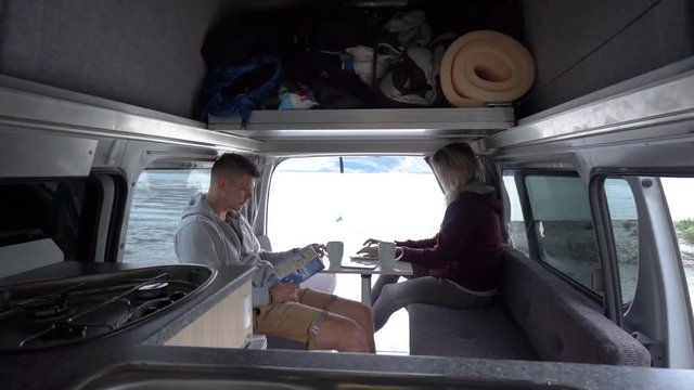 SLOWMO - Young attractive couple sitting in back of motorhome by Lake Wakatipu, Queenstown, New Zealand