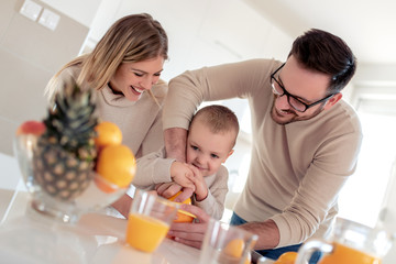 Obraz na płótnie Canvas Happy family make orange juice in morning