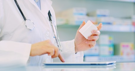 Hand close up of a  young woman pharmacist consultant checking medicines list on tablet in a drug...