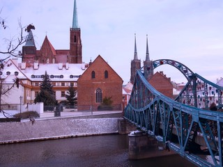 Tumski Bridge or Lovers Bridge and View of Ostrow Tumski St. Bartholomew Church with Snow on the Ground