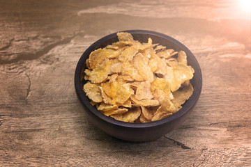 Corn flakes and bowl on wood table