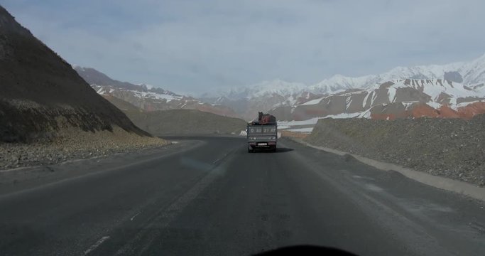 Point of view shot, inside of a moving car, following a truck with a horse on it, on a cloudy day, in Sary-tash, Kyrgyzstan