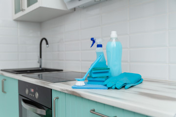 A set of blue cleaning products and tools for cleaning is on the kitchen table.