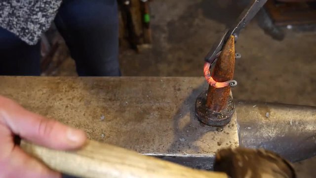 A Female Blacksmith Forging a Handmade Bracelet at the Bick on an Anvil