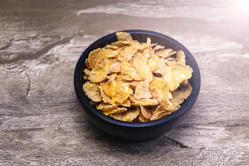 Corn flakes and bowl on wood table