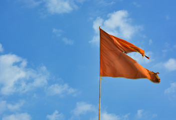 Red torn from the wind flag on the background of blue sky on the beach in Northern Goa.India 