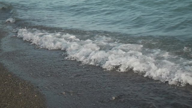 Waves crash along the shore of a beach in slow motion.
