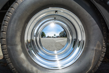 Black tire and chrome mirror cover on the wheel of vintage car