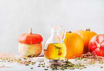 Light oil pumpkin seeds in glass jug on white rustic background - healing and healthy food concept,...