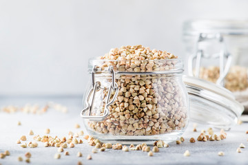 Green buckwheat in glass jar, healthy vegetarian food or raw foods concept, gray kitchen table background, selective focus