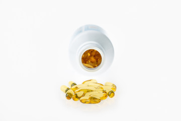 The cod liver oil capsules in the bottle isolated on white background. Cod liver oil is a dietary supplement derived from liver of cod fish (Gadidae).
