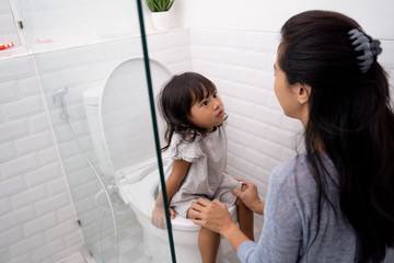 mother help her kid to use toilet. toilet training for toddler with mom