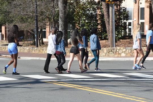 A diverse group of college students cross the street